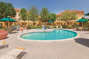 a swimming pool with chairs and umbrellas at a resort at La Quinta by Wyndham Dallas DFW Airport North in Irving