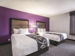 two beds in a hotel room with purple walls at La Quinta by Wyndham Hartford Bradley Airport in Windsor Locks