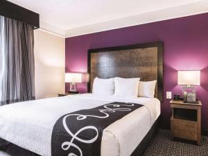 シュリーブポートにあるLa Quinta by Wyndham Shreveport Airportの紫の壁の大型ベッドが備わるホテルルームです。