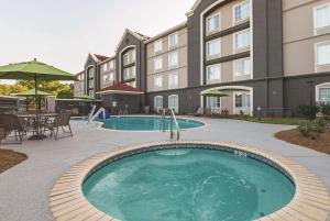 - une piscine dans un hôtel avec des tables et des chaises dans l'établissement La Quinta by Wyndham Alexandria Airport, à Alexandria