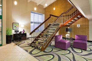 a lobby with a spiral staircase and purple chairs at La Quinta Inn by Wyndham Oshkosh in Oshkosh