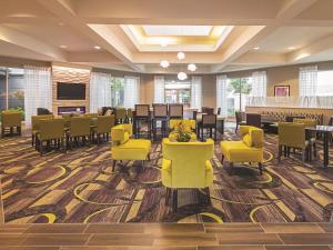 a dining room with yellow chairs and tables in a lobby at La Quinta by Wyndham Fort Worth City View in Fort Worth