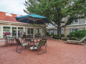 a patio with tables and chairs and an umbrella at La Quinta by Wyndham Denver Airport DIA in Denver