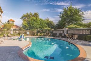 einen Pool im Garten mit Stühlen und Sonnenschirmen in der Unterkunft La Quinta by Wyndham Oklahoma City Norman in Norman