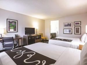 a hotel room with two beds and a desk and a television at La Quinta by Wyndham Atlanta Midtown - Buckhead in Atlanta