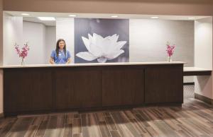 a woman standing at a reception desk in a lobby at La Quinta by Wyndham Minneapolis Bloomington W in Bloomington