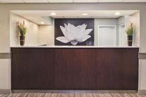 a reception desk in a lobby with a painting of a flower at La Quinta by Wyndham Charleston Riverview in Charleston