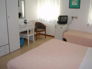 Habitación con cama y escritorio con ordenador. en Hotel Villa Carla, en Grado