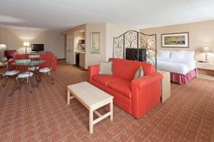 Habitación de hotel con cama y sofá rojo en La Quinta by Wyndham Garden City en Garden City