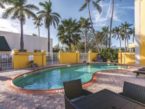 a swimming pool with chairs and palm trees at La Quinta Inn by Wyndham Jupiter in Jupiter