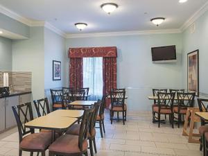 a dining room with tables and chairs and a television at La Quinta by Wyndham Slidell - North Shore Area in Slidell