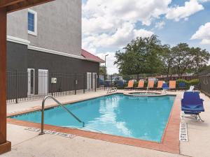 ein Pool mit blauen Stühlen und ein Gebäude in der Unterkunft La Quinta by Wyndham San Antonio Northwest in San Antonio