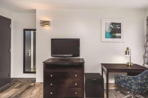 a living room with a tv on a dresser with a desk at La Quinta by Wyndham Brooklyn Downtown in Brooklyn