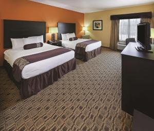 a hotel room with two beds and a television at La Quinta by Wyndham Searcy in Searcy