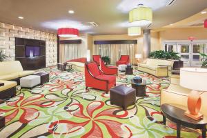 a lobby with red chairs and a large rug at La Quinta by Wyndham Hinesville - Fort Stewart in Hinesville