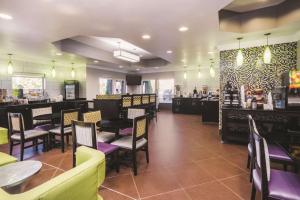 a restaurant with tables and chairs and a bar at La Quinta Inn & Suites by Wyndham Louisville East in Louisville