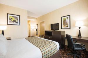 a hotel room with a bed and a desk and a television at La Quinta Inn by Wyndham Buffalo Airport in Williamsville