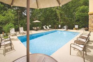 - une piscine avec des chaises et un parasol dans l'établissement La Quinta by Wyndham Smyrna TN - Nashville, à Smyrna