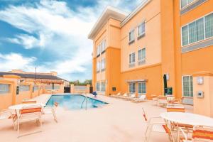 a pool with tables and chairs next to a building at La Quinta by Wyndham Cotulla in Cotulla
