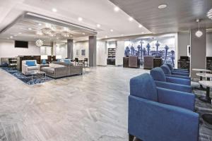 a lobby with blue chairs and tables in a building at La Quinta by Wyndham Victoria - South in Victoria