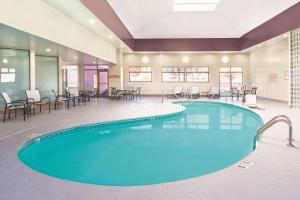 a pool in a hotel room with chairs and tables at La Quinta by Wyndham Loudon in Loudon