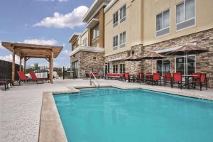 a swimming pool with tables and chairs and a building at La Quinta by Wyndham San Antonio by Frost Bank Center in San Antonio