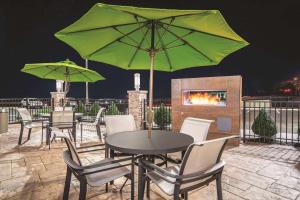 a table and chairs with a green umbrella on a patio at La Quinta by Wyndham Cleveland TN in Cleveland