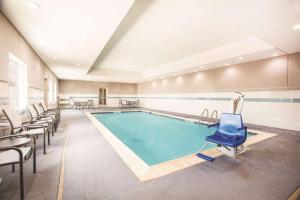 a swimming pool with a blue chair in a room at La Quinta by Wyndham Dallas Plano - The Colony in The Colony