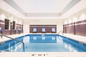 a pool in a hotel with tables and chairs at La Quinta by Wyndham Wichita Northeast in Wichita