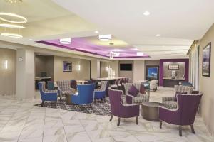 a waiting room with blue chairs and a bar at La Quinta by Wyndham Springfield IL in Springfield