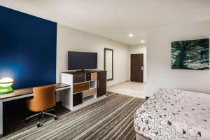 a hotel room with a bed and a desk with a tv at La Quinta by Wyndham Owasso in Owasso