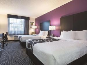 two beds in a hotel room with purple walls at La Quinta by Wyndham Plantation at SW 6th St in Plantation