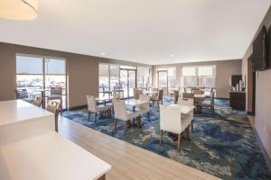 uma sala de jantar com mesas, cadeiras e janelas em La Quinta by Wyndham Philadelphia Airport em Essington