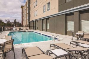 a pool with tables and chairs next to a building at La Quinta Inn & Suites by Wyndham Atlanta South - McDonough in McDonough