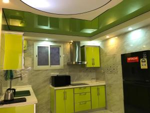 uma cozinha com armários verdes e um frigorífico preto em Deluxe Furnished Apartments em Taif