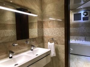 a bathroom with a sink and a mirror and a tub at Deluxe Furnished Apartments in Taif