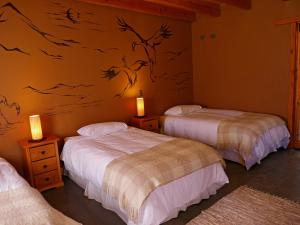 a bedroom with two beds and a painting on the wall at Terra Luna Atacama in San Pedro de Atacama