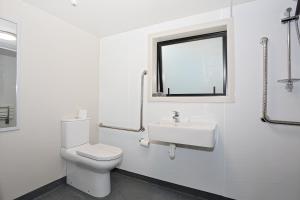 a white bathroom with a toilet and a sink at Shakespeare House in Te Anau