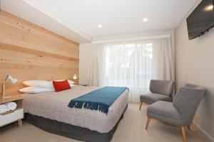 a bedroom with a bed and a chair at Shakespeare House in Te Anau