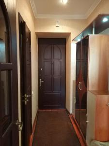 a hallway with a black door and a refrigerator at Apartment Lux on Univermag Ukraina Center, 76 in Zaporozhye