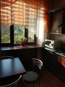 a kitchen with a table and chairs and a microwave at Apartment Lux on Univermag Ukraina Center, 76 in Zaporozhye