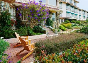 a wooden bench sitting in a garden with flowers at La Playa Hotel in Carmel