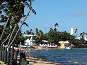a beach with umbrellas and people on the water at Mandacaru Guest House in Praia do Forte