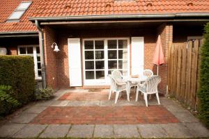 eine Terrasse mit Tisch und Stühlen vor einem Haus in der Unterkunft 50158... in Carolinensiel