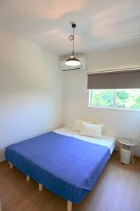 a bedroom with a blue bed and a window at 2019新築 ! guest house Holoholo beach side in Ishigaki Island