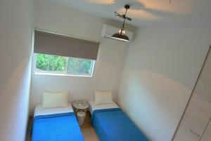 a small room with two beds and a window at 2019新築 ! guest house Holoholo beach side in Ishigaki Island
