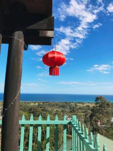 a red chandelier hanging from a balcony overlooking the ocean at The Goat and Goose Bed & Breakfast in Lakes Entrance