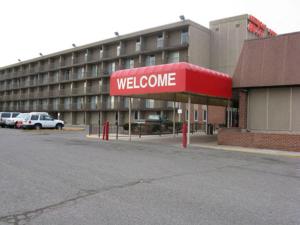 a building with a red welcome sign in a parking lot at American Motel in Wheat Ridge
