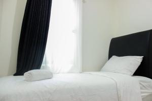 a bed with a white blanket and a window at Direct Access to Pool 2BR Apartment at Parahyangan Residence By Travelio in Bandung