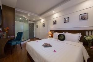a bedroom with a large white bed and a blue chair at Hanoi Amber Hotel in Hanoi